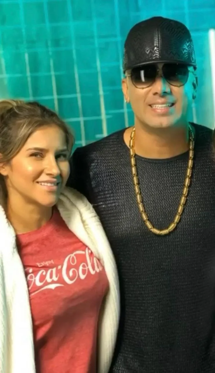 Moni Aristi with an artist wearing a cap and gold chain backstage