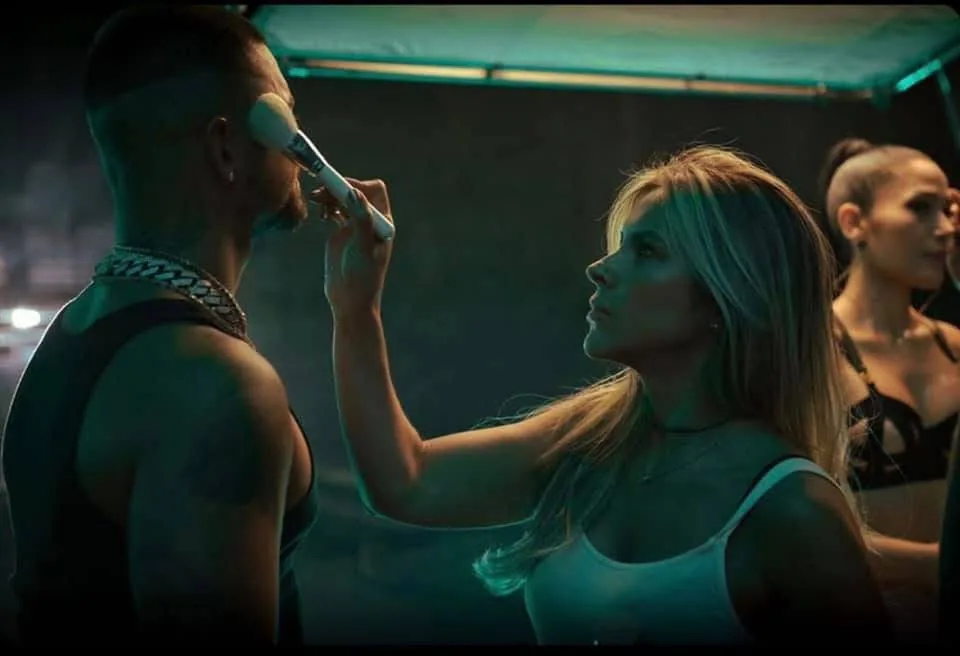 Touching up an artist's makeup under neon light on set