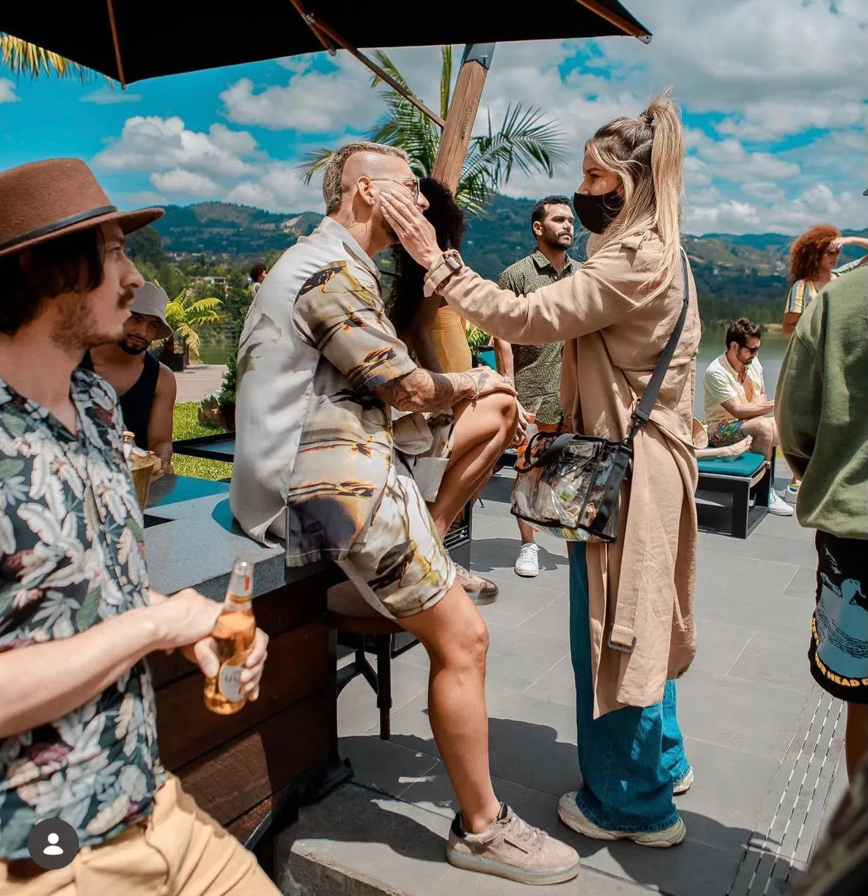 Moni Aristi touching up an artist's makeup at a lakeside event