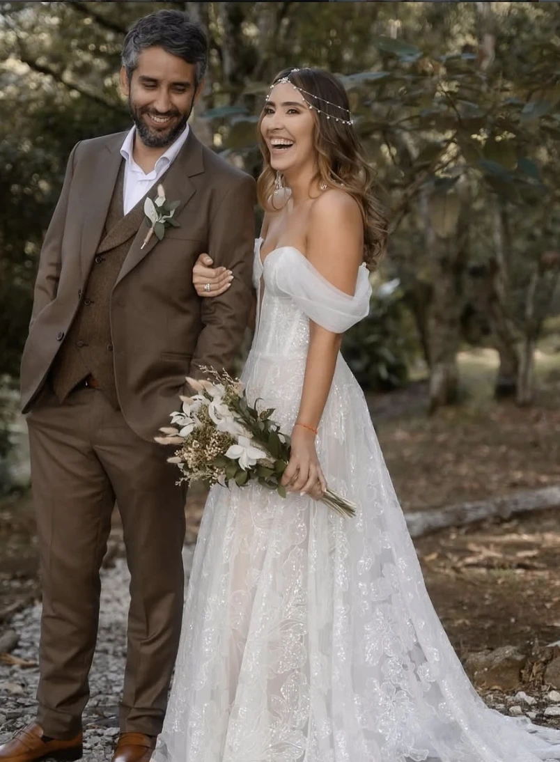 Newlyweds laughing arm in arm along a forest path