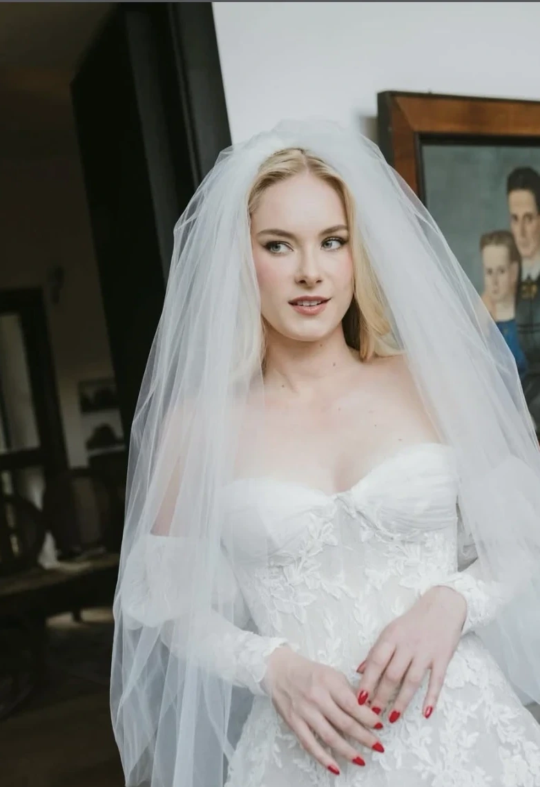 Blonde bride with a lace veil and luminous natural makeup, looking to the side