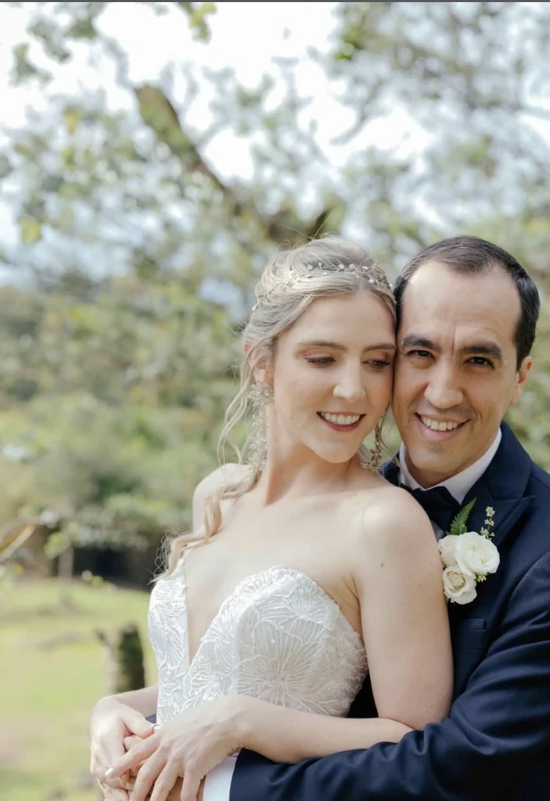 Newlyweds embracing in a flowering garden, bride wearing a pearl headpiece