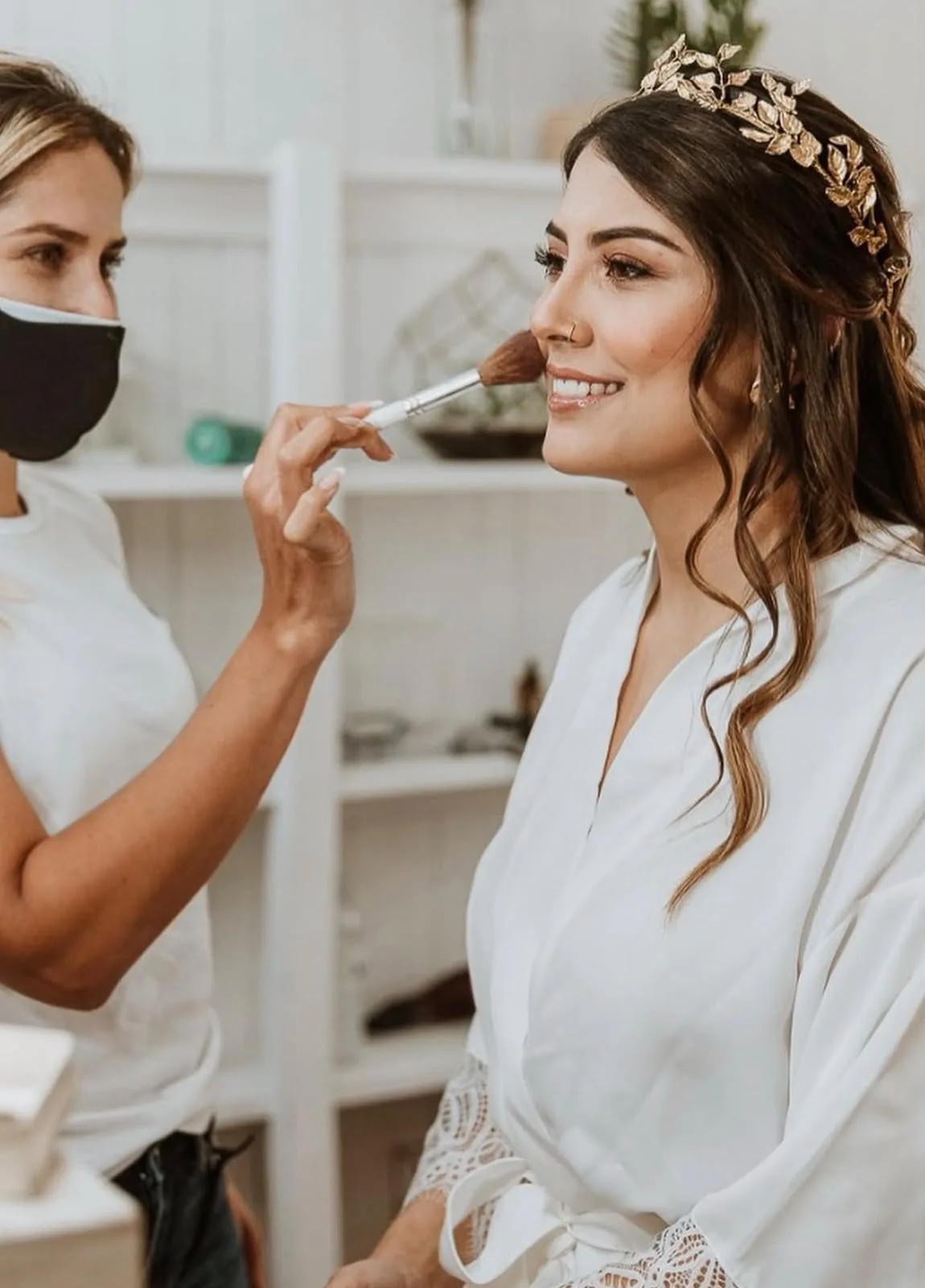 Moni Aristi applying blush to a bride wearing a gold leaf headpiece