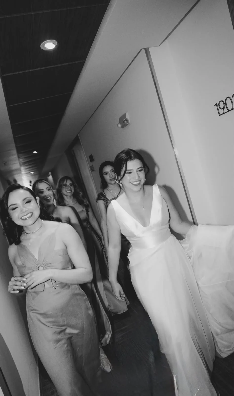 Bride and her bridesmaids laughing in the hotel hallway before the ceremony